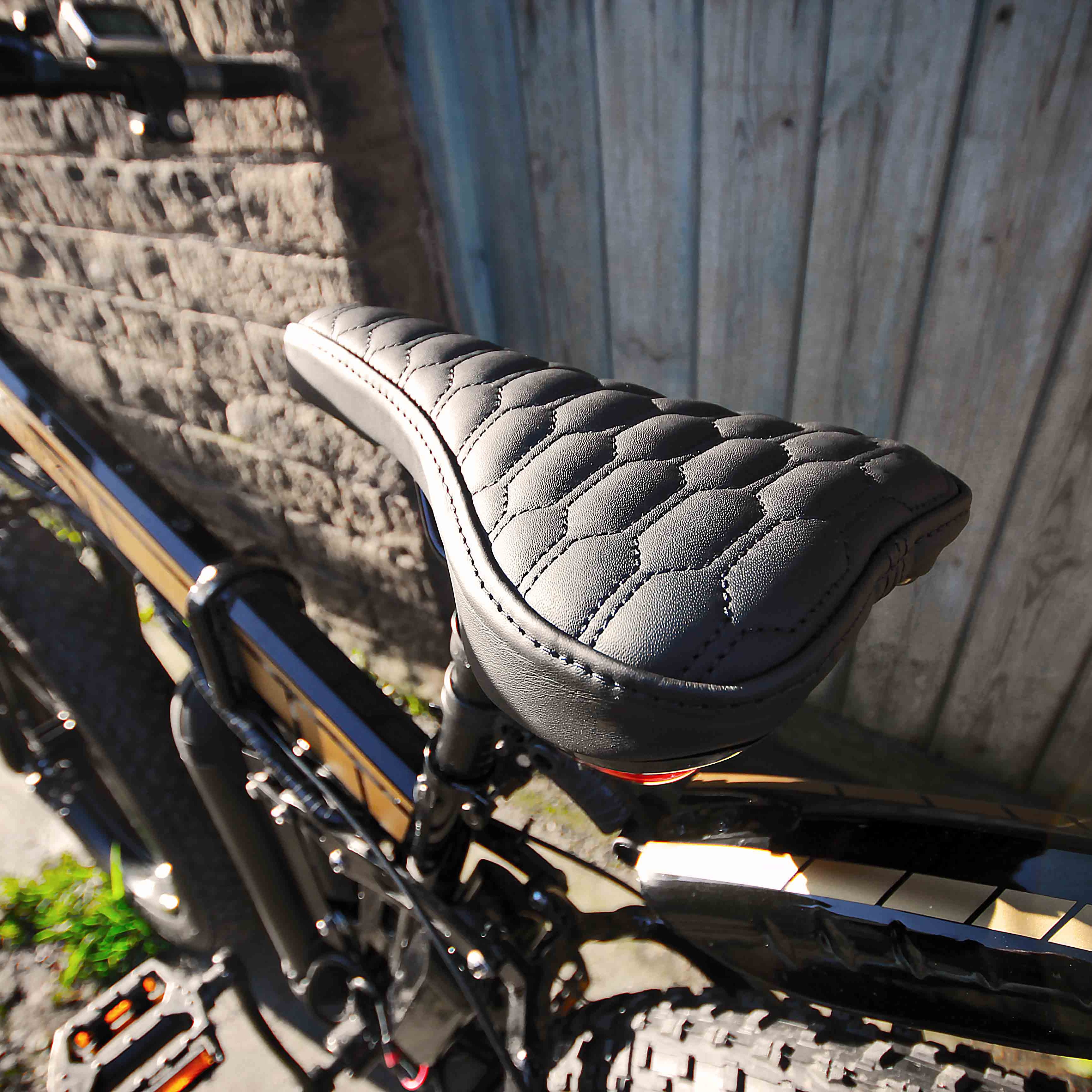 Close-up of a bicycle seat with a textured pattern against a wooden wall.