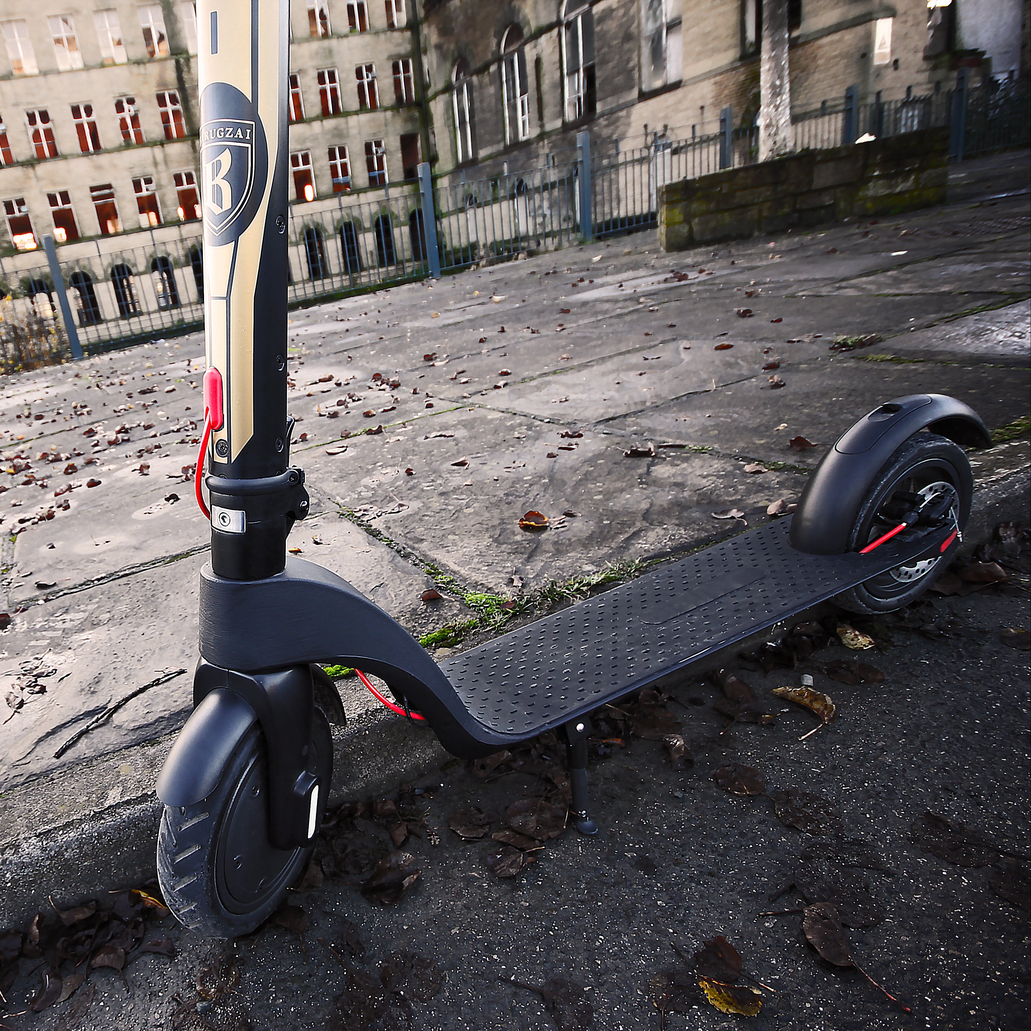 Black scooter leaning against a wall with a building in the background