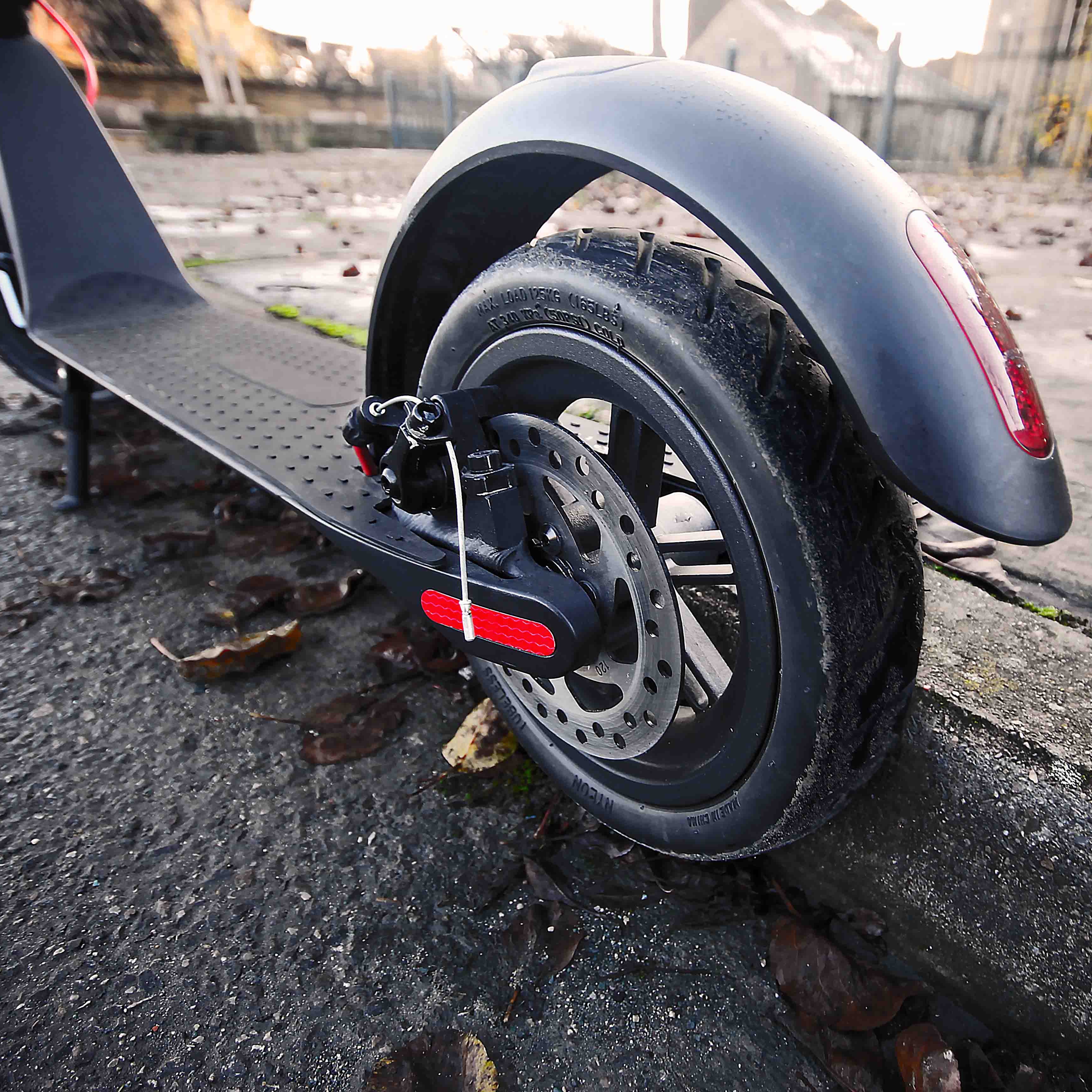 Close-up of a scooter's wheel and suspension system on a street.
