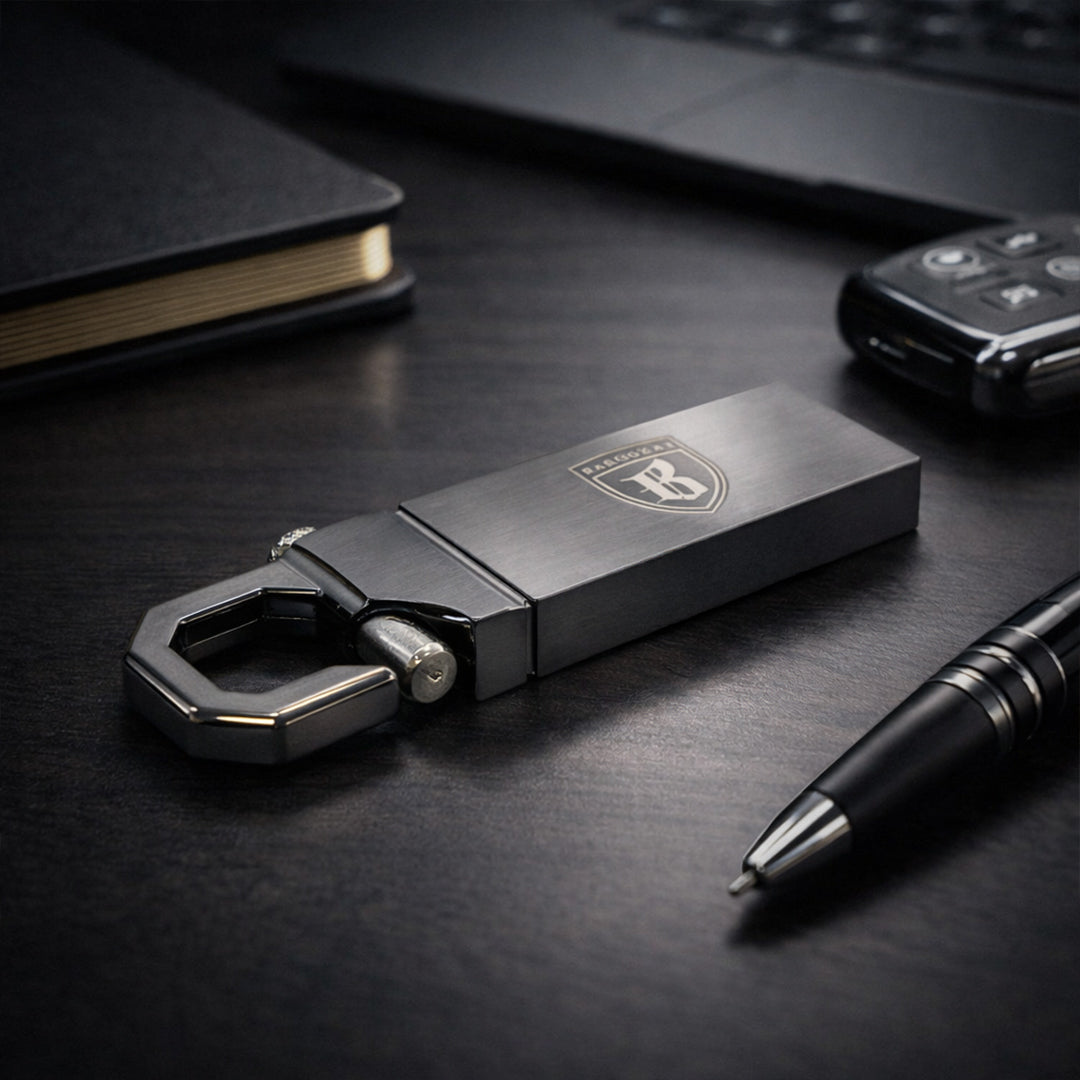 Black bottle opener with car keychain attachment on a dark surface with a pen and laptop.