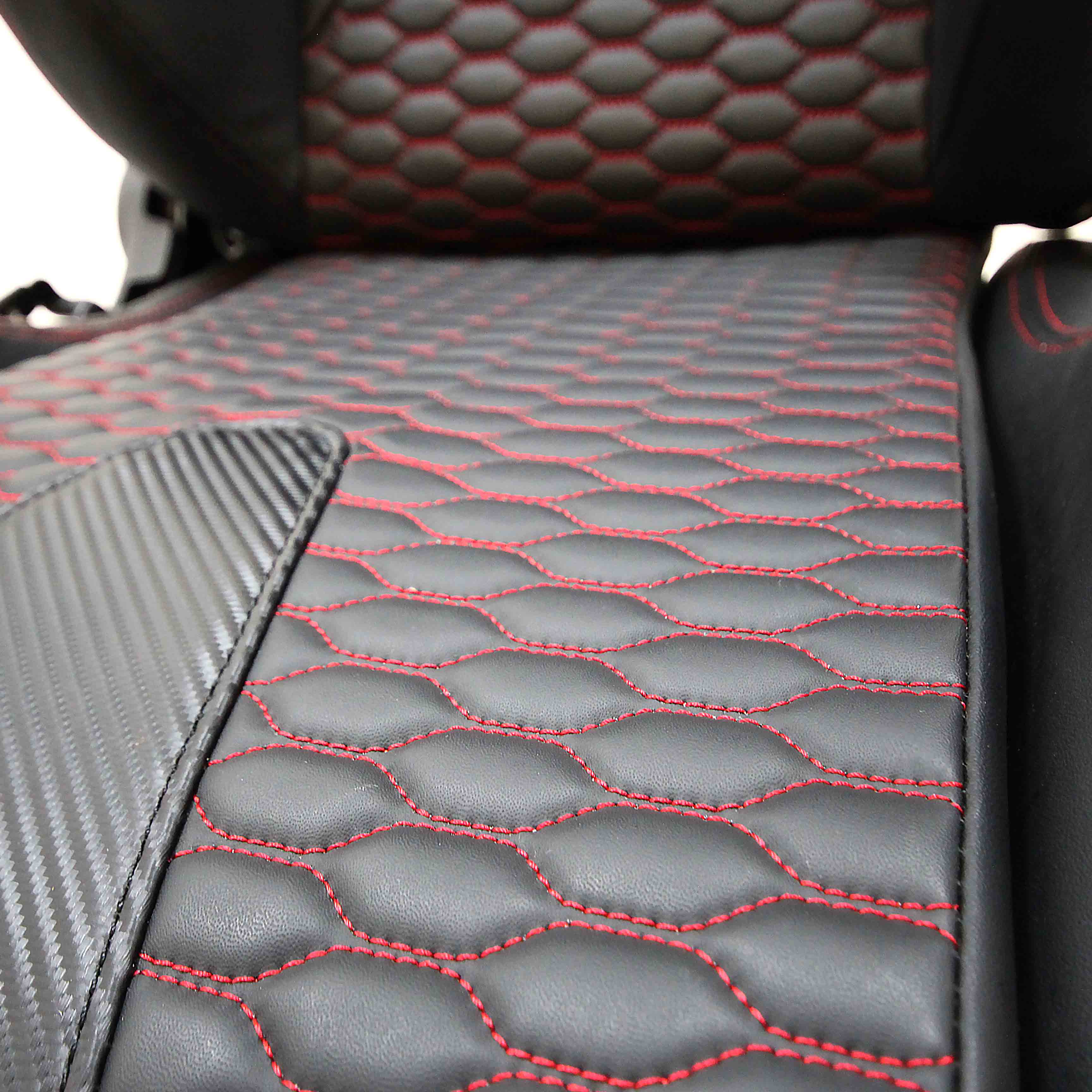 Close-up of a red and black car seat with red stitching on a white background.