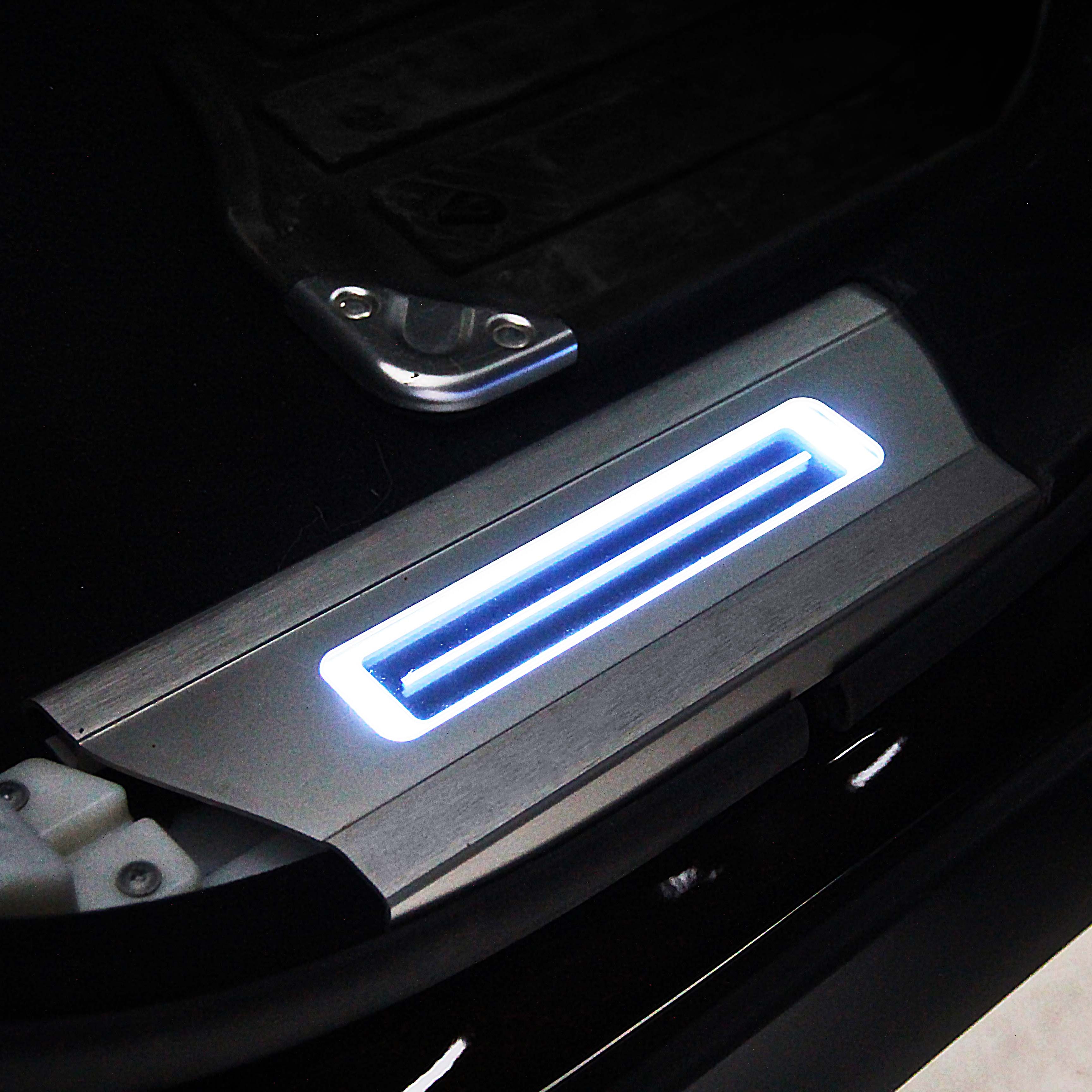 Car door sill plates with a blue light on a dark interior background.
