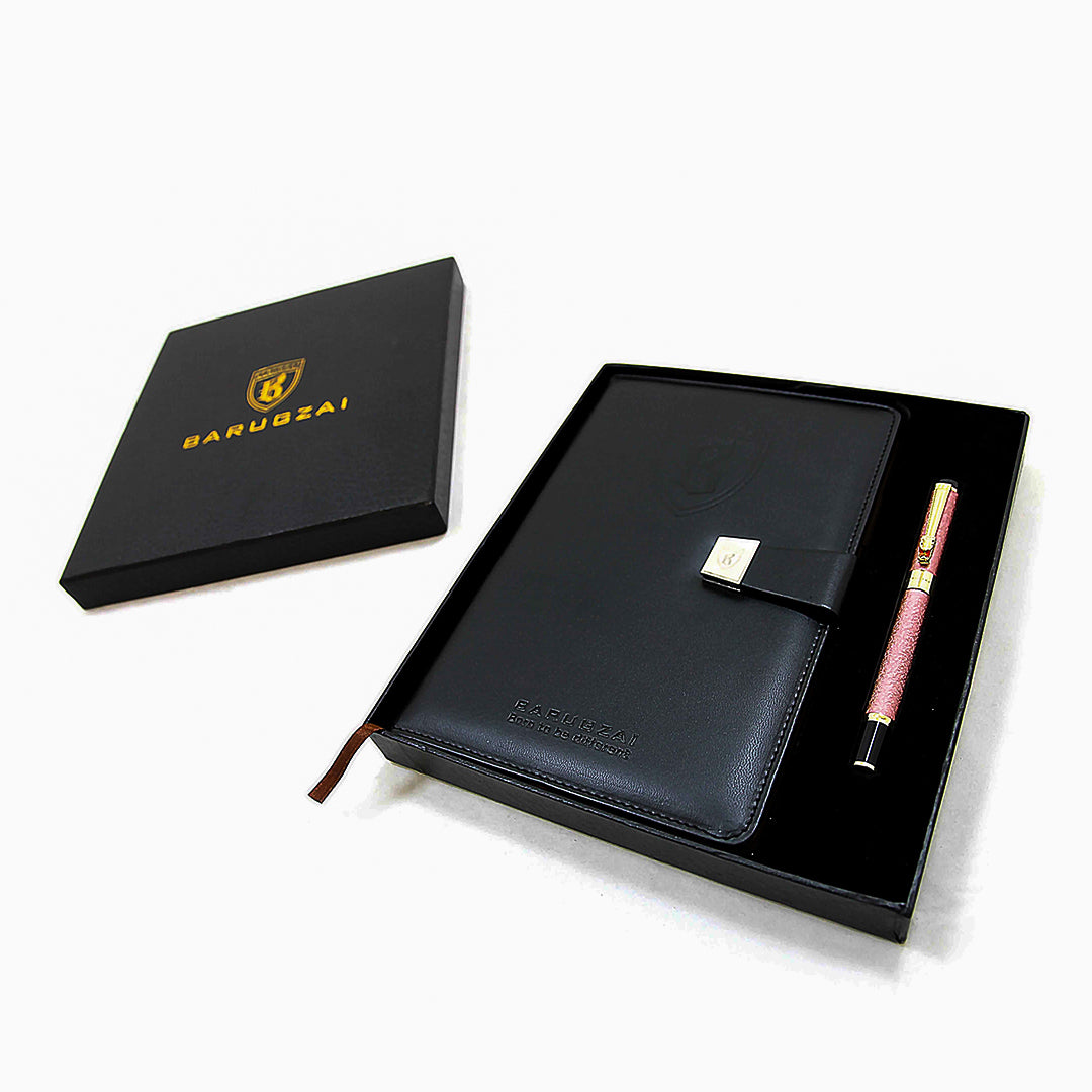 Black leather notebook with pink pen and box on a white background.