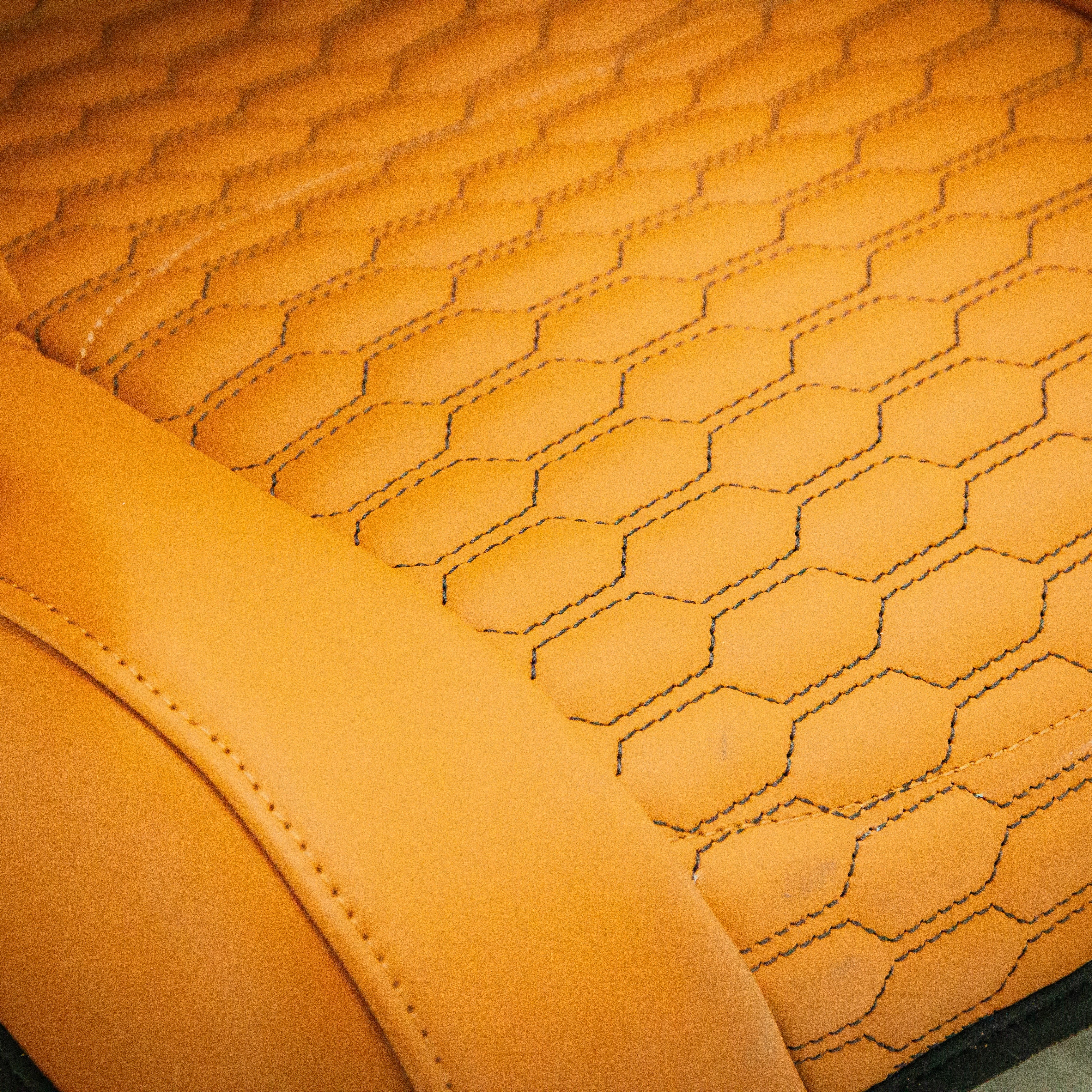 Close-up of a quilted orange seat cover with hexagonal pattern