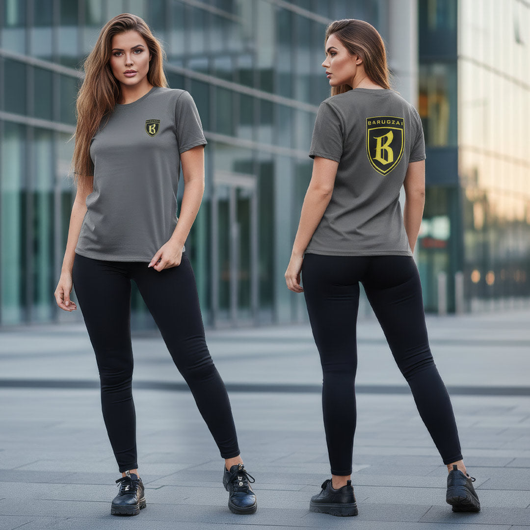 Woman wearing a gray t-shirt with a gold and black barugzai logo, standing in front of a modern building.