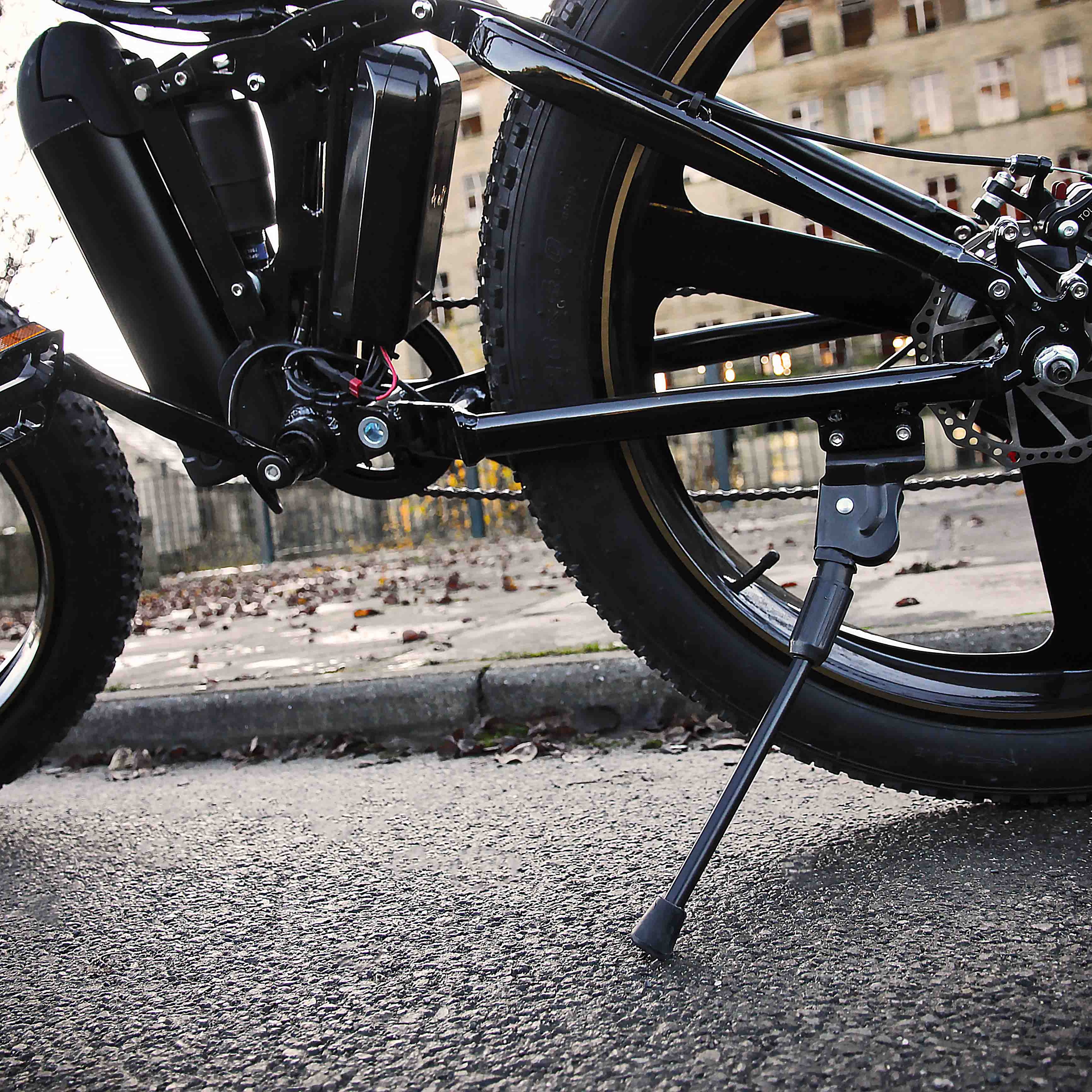Close-up of a black electric bike with visible mechanical components on an urban street.