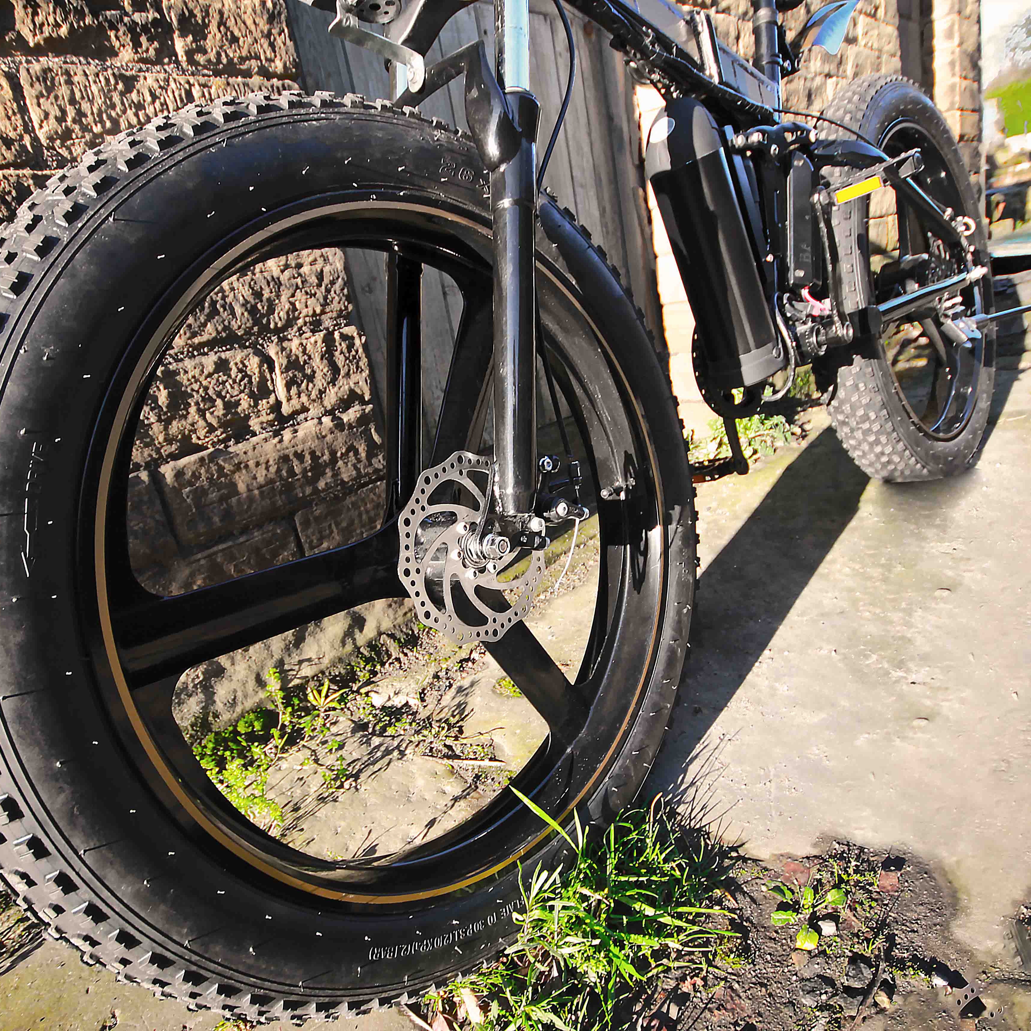 Close-up of a bicycle tire with tread pattern on a stone pavement.