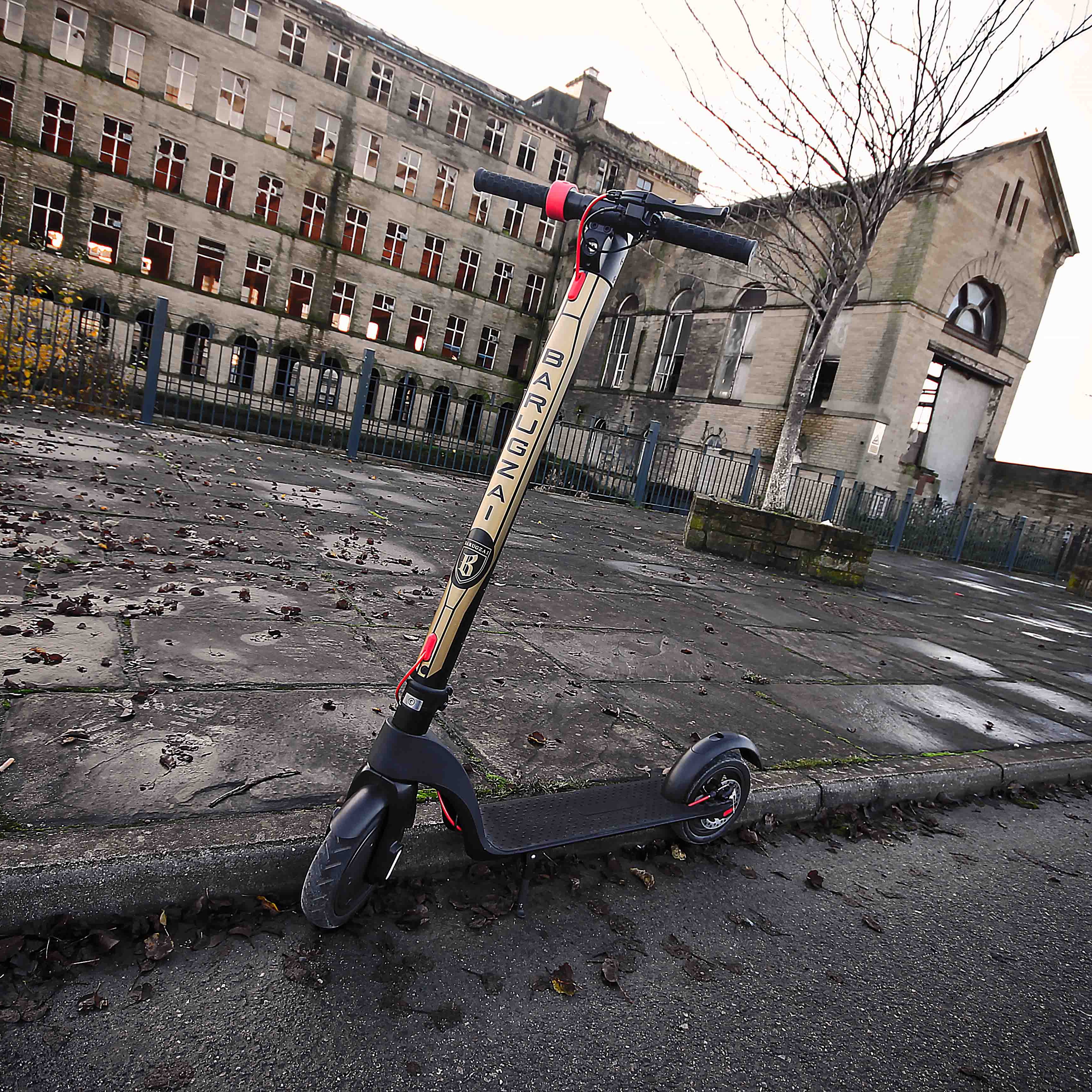 Electric scooter leaning against an abandoned building with a desolate street.