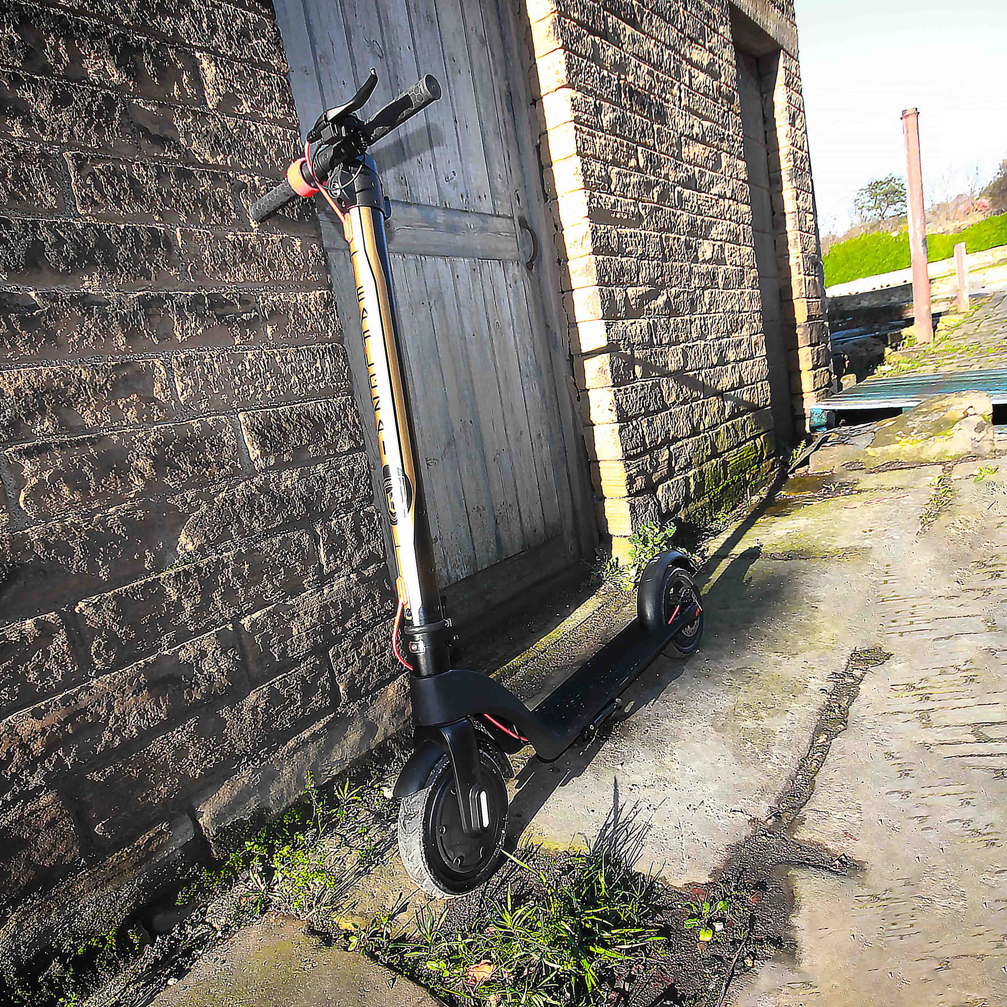 Electric scooter leaning against a brick wall on a cobblestone street.