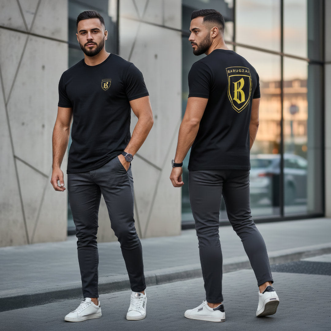 Man wearing a black t-shirt with a yellow barugzai logo, standing in front of a modern building.