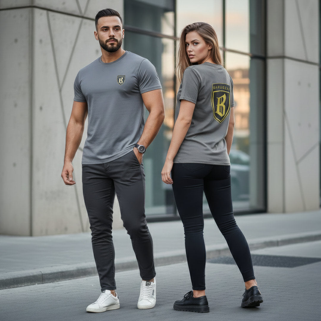 Man and woman wearing matching gray t-shirts with a gold barugzai logo on a city street.