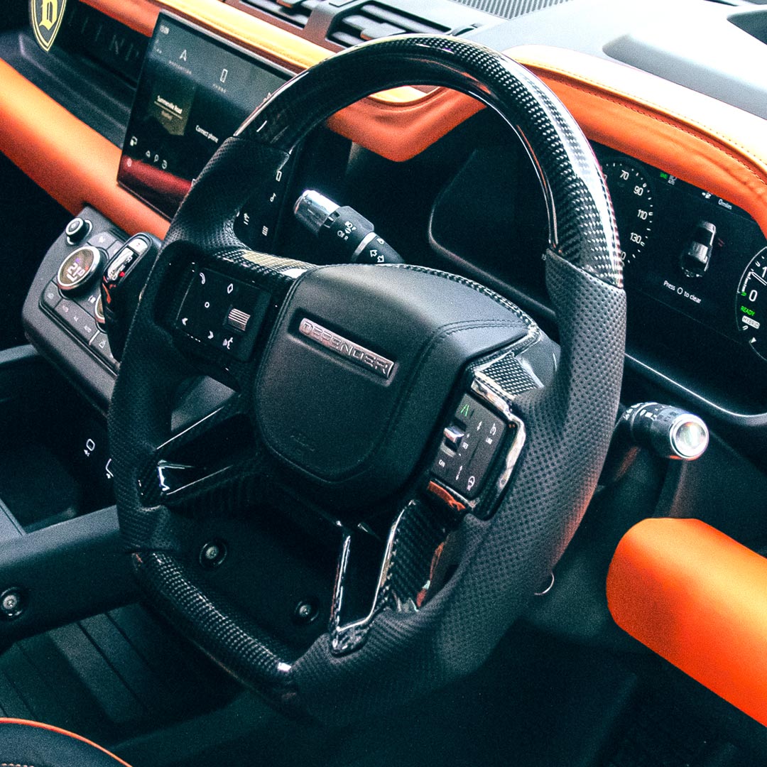 Steering wheel and dashboard of a luxury vehicle with orange accents
